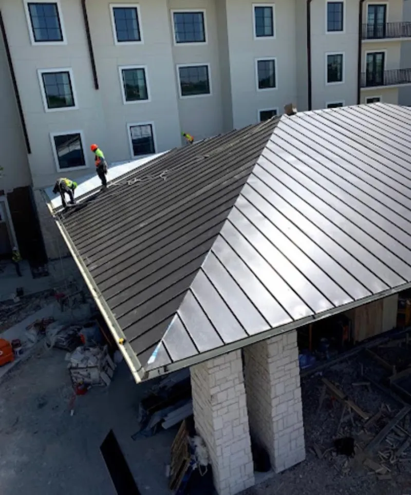 Crew installing standing seam metal roof panels on a commercial project in Seymour